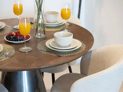 a wooden table with a bowl of fruit and glasses of orange juice at Downtown Burj Khalifa View 2BR Apartment in Dubai