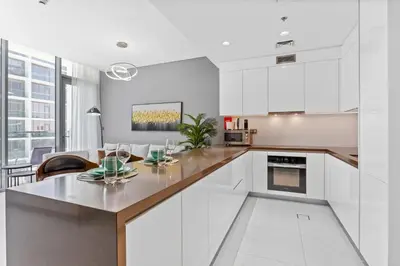 a kitchen with white cabinets and a table and chairs at Premium 1-BR with Exquisite Layout in District One in Dubai