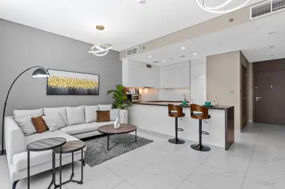 a living room with a white couch and a kitchen at Premium 1-BR with Exquisite Layout in District One in Dubai
