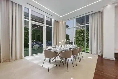 a dining room with a table and chairs and windows at Palm Penthouse Sky Villa - Vast Terrace & Jacuzzi by Exclusive Holiday Homes in Dubai