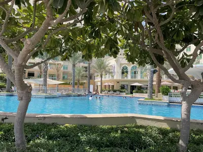 a swimming pool with trees in front of a building at Dabas Palm Shores Elegant Four Beds in Dubai