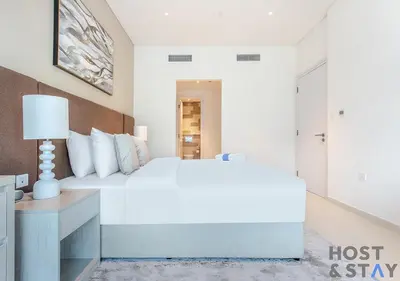 a white bedroom with a large bed and a desk at Luxurious 1BR Palm Seven, Palm Jumeirah in Dubai