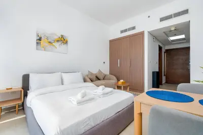 a bedroom with a large white bed and a couch at Nice studio in Al Furjan - Dubai in Dubai
