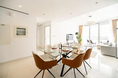 a living room with a dining room table and chairs at SettlerHomes - Breathtaking View With Private Beach in Dubai