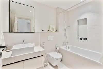 a white bathroom with a sink and a toilet at Beachfront 2-BDR, High floor, Sea and Palm View, Beach Access in Dubai