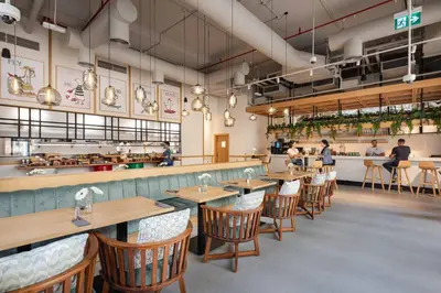a restaurant with wooden tables and chairs and a counter at Rove JBR in Dubai