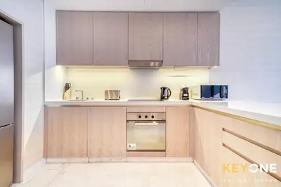 a kitchen with wooden cabinets and a stove at Iconic One Bedroom Panoramic Palm Views in Dubai