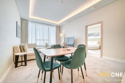 a dining room with a table and green chairs at Iconic One Bedroom Panoramic Palm Views in Dubai