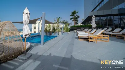 a pool with chairs and umbrellas on a building at Iconic One Bedroom Panoramic Palm Views in Dubai