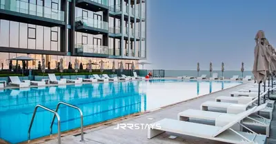 a swimming pool with white lounge chairs next to a building at Stunning Luxury 1BR - Modern with Pool View - JVC in Dubai