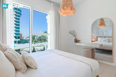 a white bedroom with a bed and a large window at HiGuests - Ocean Views and Comfort in La Vie, JBR in Dubai