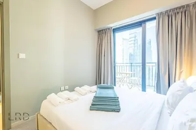 a bedroom with a bed and a large window at Cozy & Radiant 1BR Business Bay in Dubai