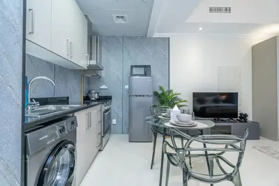 a kitchen with a washing machine and a table with chairs at Escape24 Cozy 1BR near Dubai Malll & Burj Khalifa in Dubai