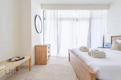 a bedroom with a bed and a desk and a window at Modern & Vibrant 1BR Dubai Hills in Dubai