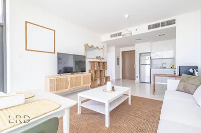 a living room with a white couch and a table at Modern & Vibrant 1BR Dubai Hills in Dubai
