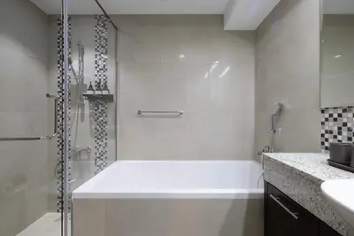 a white bath tub in a bathroom with a shower at Iconic Burj Khalifa Views from Luxury 1BR Home in Dubai
