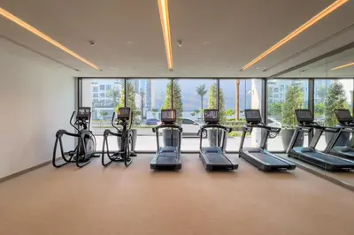 a gym with several cardio machines in a room with windows at GuestReady - Upscale living at Palace Residence in Dubai
