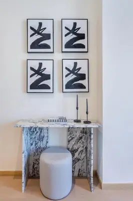 a console table with a stool and paintings on the wall at Modern Comfort1BR RP Heights 5-min Dubai Mall in Dubai