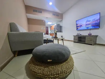 a living room with a chair and a ottoman at Stunning Apartment, Partial Sea View, Canal Marina View, 5 min walk To JBR Beach and METRO in Dubai