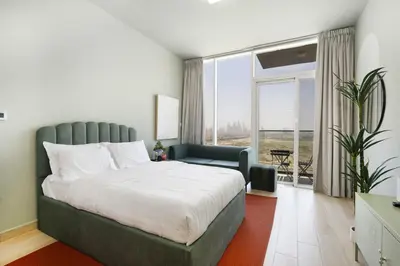 a bedroom with a large bed and a large window at Cosy Studio Apartment in Bloom Towers, Jumeirah Village Circle in Dubai