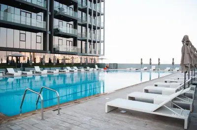 a swimming pool with white lounge chairs next to a building at Cosy Studio Apartment in Bloom Towers, Jumeirah Village Circle in Dubai