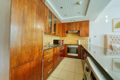 a kitchen with wooden cabinets and a sink at Luxury Studio - Downtown Dubai 6 Minute Walk to Burj Khalifa & Dubai Mall in Dubai