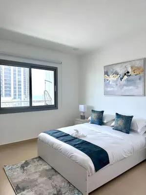 a white bedroom with a bed and two windows at Luxury sea-view apartment in Dubai