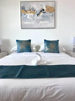 a white bed with blue pillows in a bedroom at Luxury sea-view apartment in Dubai