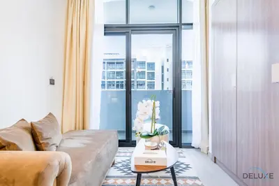 a living room with a couch and a table with flowers at Charming Studio at Azizi Riviera 32, Al Merkadh by Deluxe Holiday Homes in Dubai