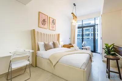 a bedroom with a large white bed and a desk at Charming Studio at Azizi Riviera 32, Al Merkadh by Deluxe Holiday Homes in Dubai
