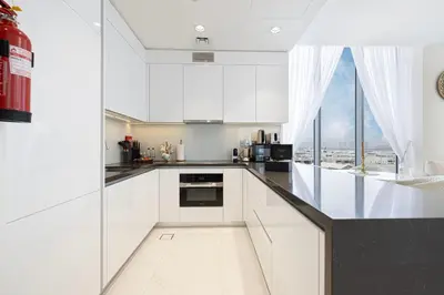 a kitchen with white cabinets and a large window at Luxury Apt Burj Khalifa, Sunset and Lagoon view in Dubai