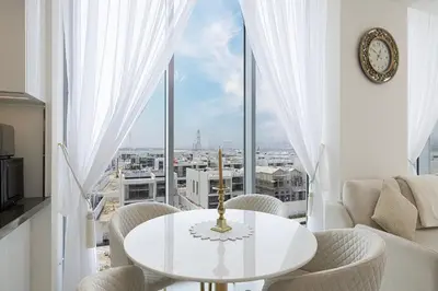 a white table and chairs in a room with a large window at Luxury Apt Burj Khalifa, Sunset and Lagoon view in Dubai