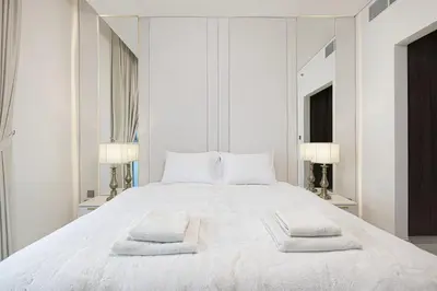 a white bedroom with a large white bed with two pillows at Luxury Apt Burj Khalifa, Sunset and Lagoon view in Dubai