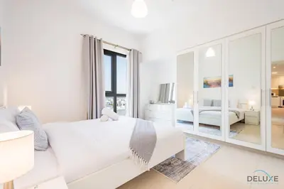 a white living room with a white couch and a bedroom at Delightful 2BR Apartment in Town Square Safi 1A, Dubailand by Deluxe Holiday Homes in Dubai