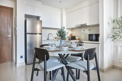 a kitchen with a table with chairs and a refrigerator at Frank Porter - Park Point Building C in Dubai