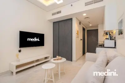 a living room with a couch and a tv on a wall at Studio in Samana Golf Avenue - Dubai in Dubai
