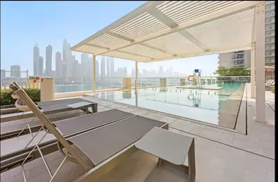 a balcony with a table and chairs and a pool at Spacious 2 BHK next to the Beach - Sunrise Bay in Dubai