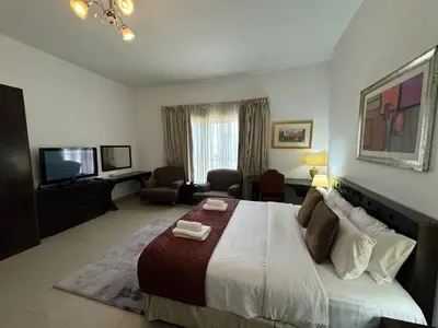 a bedroom with a large bed and a living room at ASHRI HH, Studio in JVC Dana Tower in Dubai