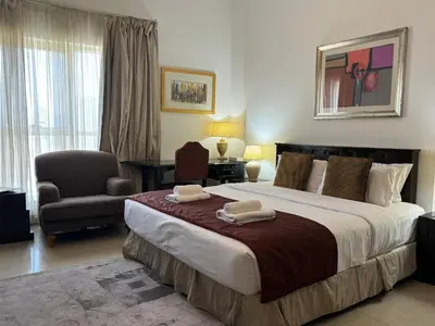 a bedroom with a large bed and a chair at ASHRI HH, Studio in JVC Dana Tower in Dubai