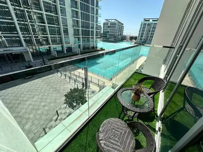 a balcony with two chairs and a swimming pool at Spacious 1bedroom W Lagoon In Al Maktoum City in Dubai