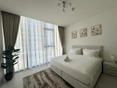a bedroom with a white bed and a large window at Spacious 1bedroom W Lagoon In Al Maktoum City in Dubai