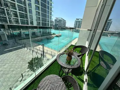 a balcony with a table and chairs and a pool at Spacious 1bedroom W Lagoon In Al Maktoum City in Dubai