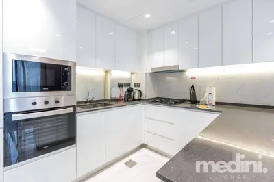 a white kitchen with a stove and a microwave at 2 bhk with Private Pool - Samana Golf Avenue - Dubai in Dubai