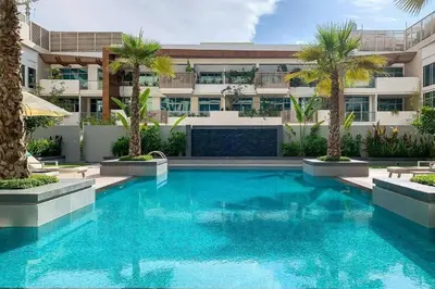a swimming pool in front of a building with palm trees at Oxford Boulevard - Studio - JVC Dubai in Dubai