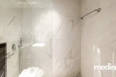 a white bathroom with a shower and a sink at Oxford Boulevard - Studio - JVC Dubai in Dubai