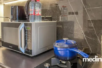 a blender and a microwave with water bottles on top at Oxford Boulevard - Studio - JVC Dubai in Dubai