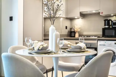 a white dining room table with chairs and a white vase at The Smarft Concierge - Sobha Creek Vista in Dubai