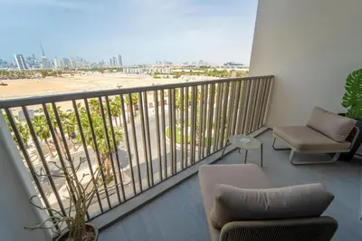 a balcony with a couch and a chair and a beach at AWS Holiday Homes - Chic Downtown Views in Dubai