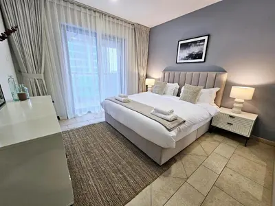a bedroom with a large bed and a large window at Spacious 1-BR close to Barasti Beach and Marina Walk in Dubai