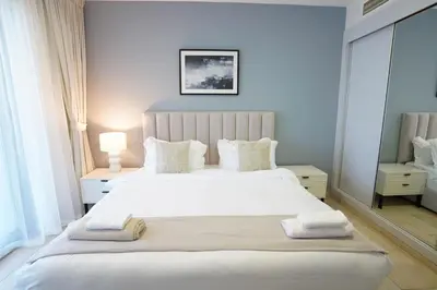 a bedroom with a large white bed with towels on it at Spacious 1-BR close to Barasti Beach and Marina Walk in Dubai